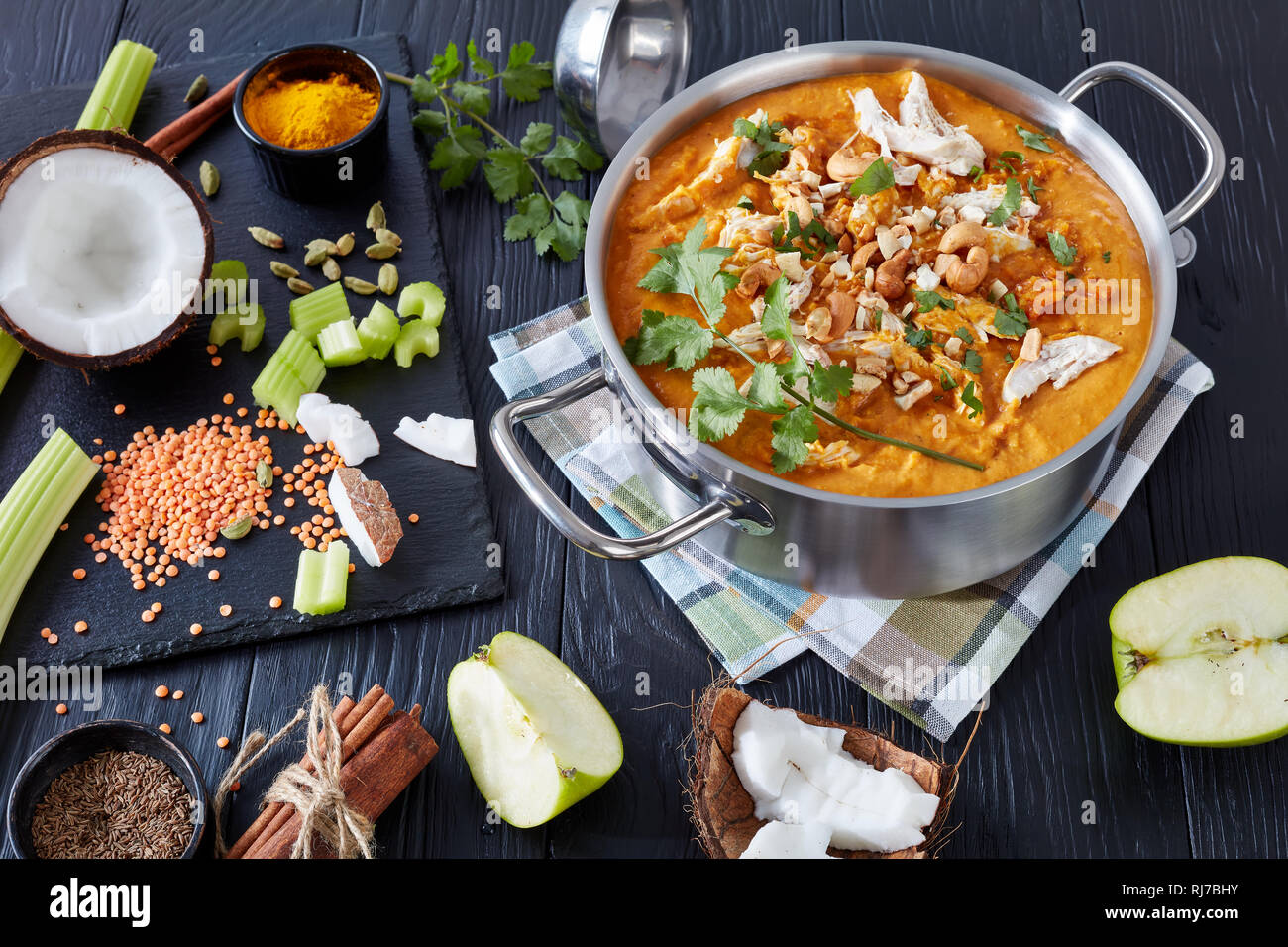 Soupe Mulligatawny épicé copieux avec de la viande de poulet frit arrosé avec dans un chaudron de cajou sur une table en bois noir avec des ingrédients, Affaires indiennes et l'engl Banque D'Images