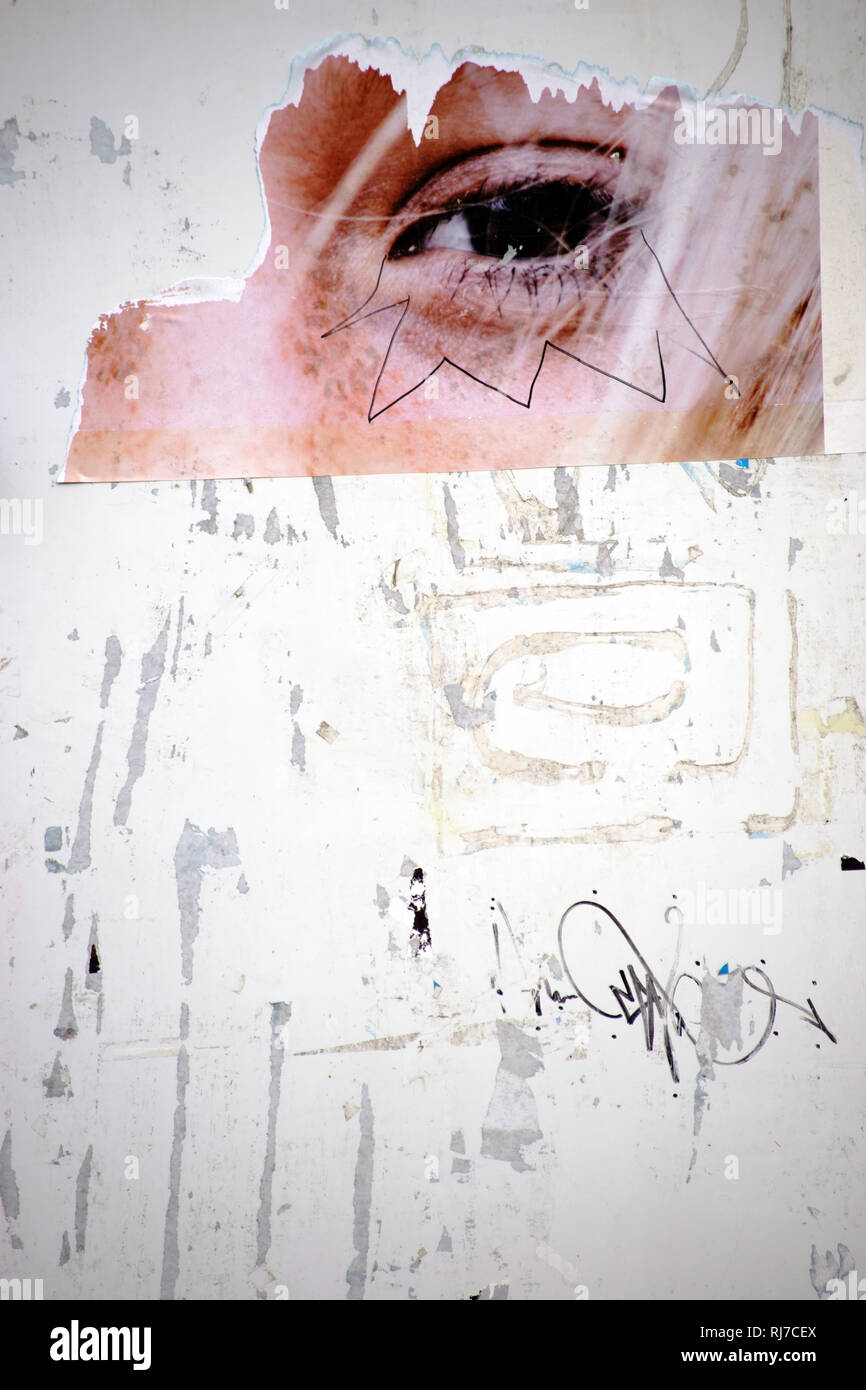Plakatwand abgerissenen mit einer Nahaufnahme von Papierfetzen Werbeplakaten Poterne und mit dem Auge einer jungen Frau. Banque D'Images