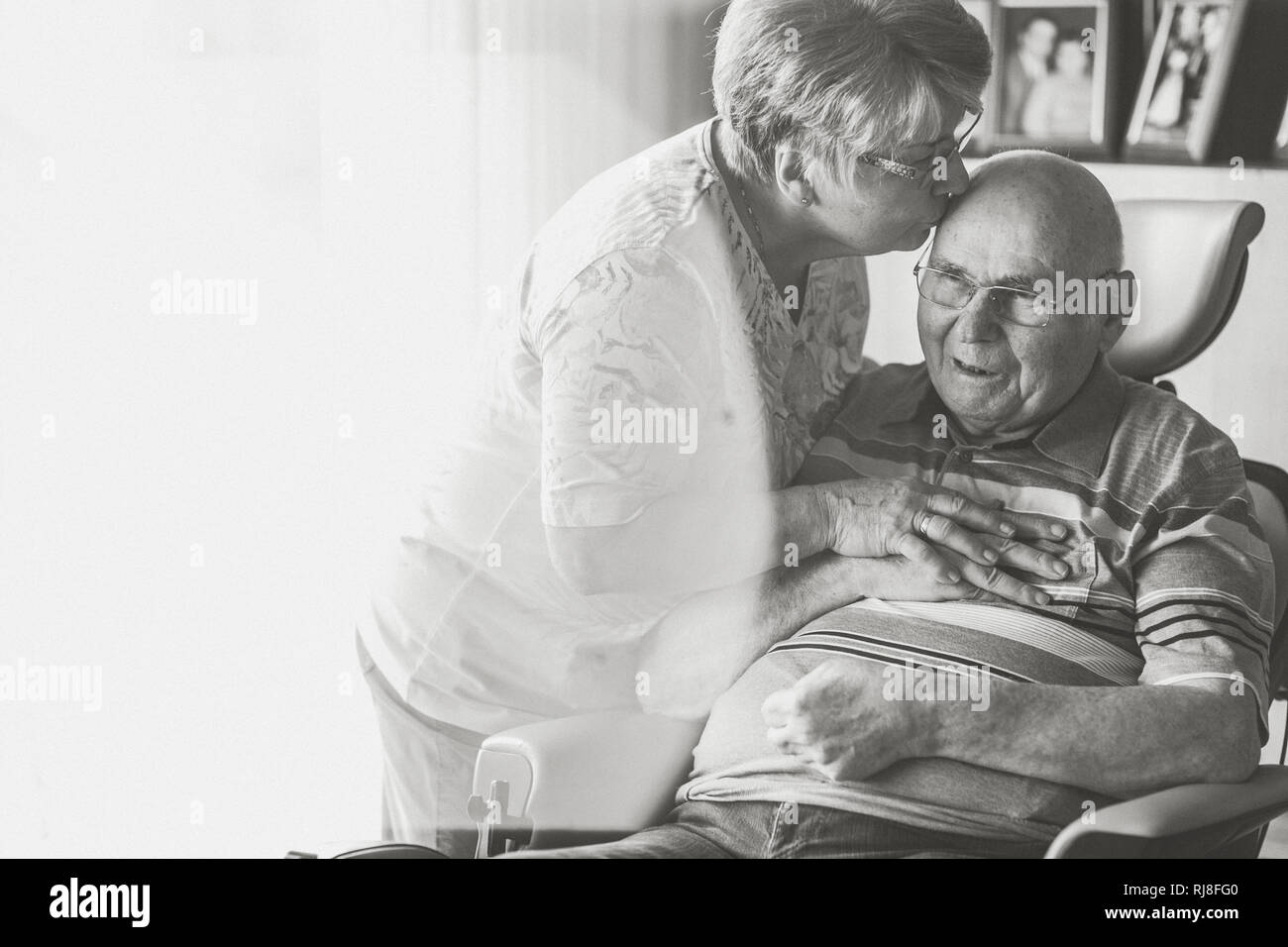 Seniorenpaar, Mann im rollstuhl, Frau küsst ihn auf die Stim, s/w Banque D'Images