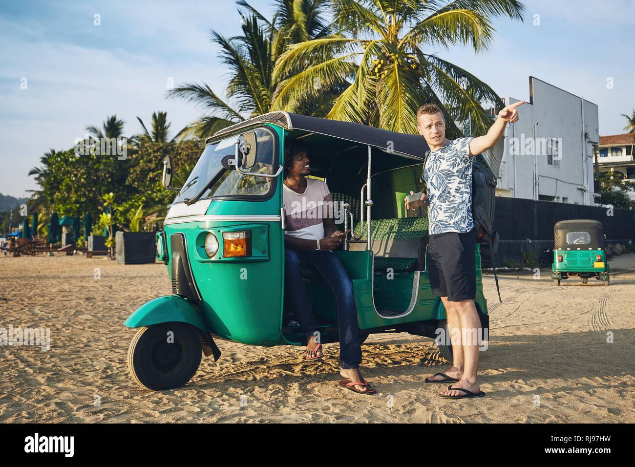 Tuk Tuk driver avec passager à plage de sable fin au Sri Lanka. Banque D'Images
