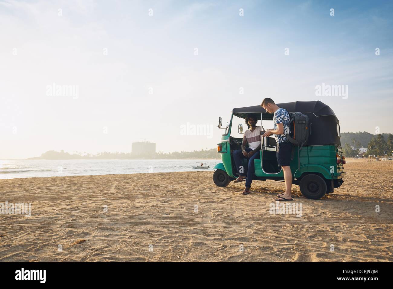 Tuk Tuk driver avec passager à plage de sable fin et la mer au Sri Lanka. Banque D'Images