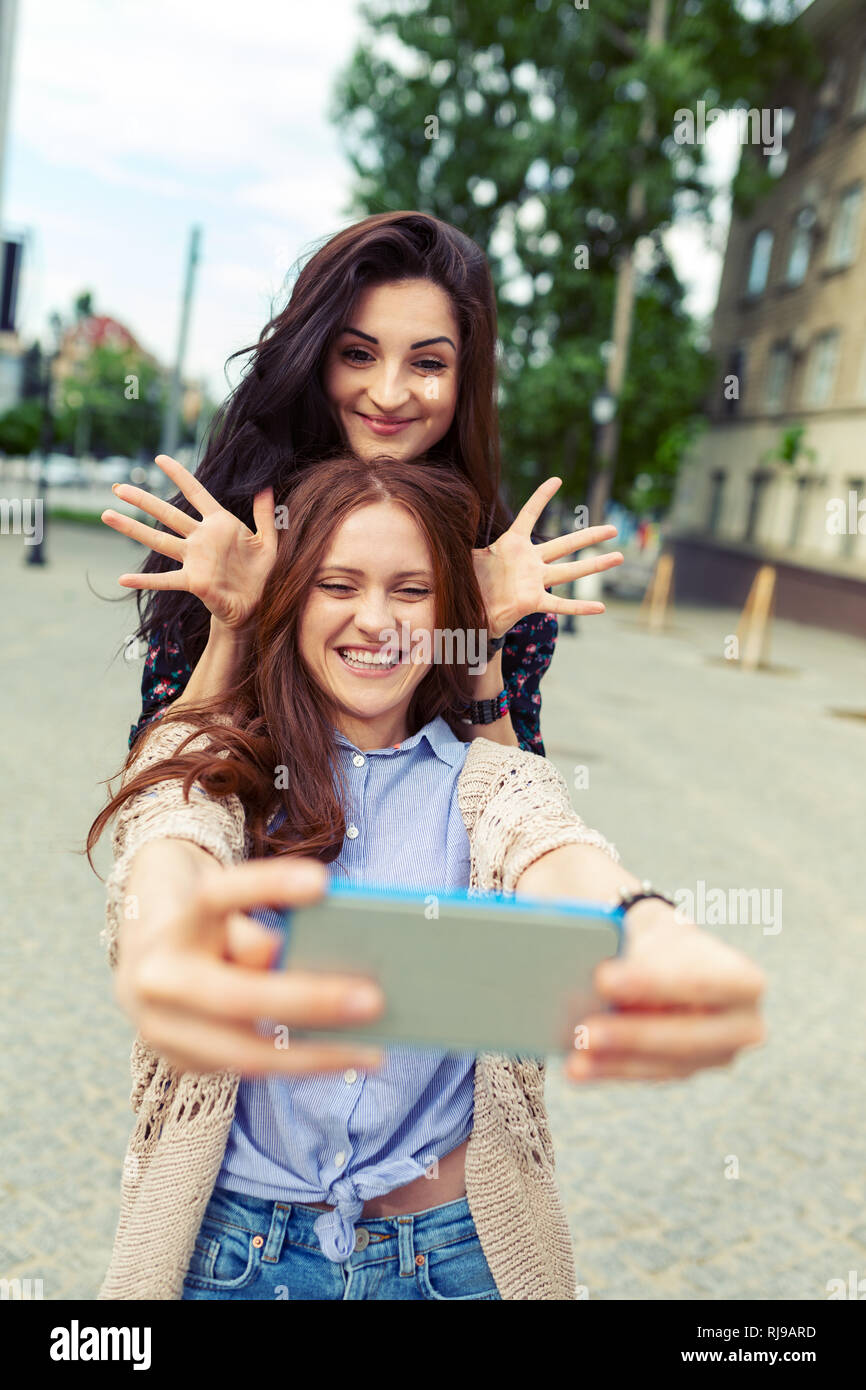 Jolies filles mignonnes selfies making funny dans la rue, de s'amuser ensemble, de joie, de bonheur, d'amour, d'amitié, de soeurs. Banque D'Images