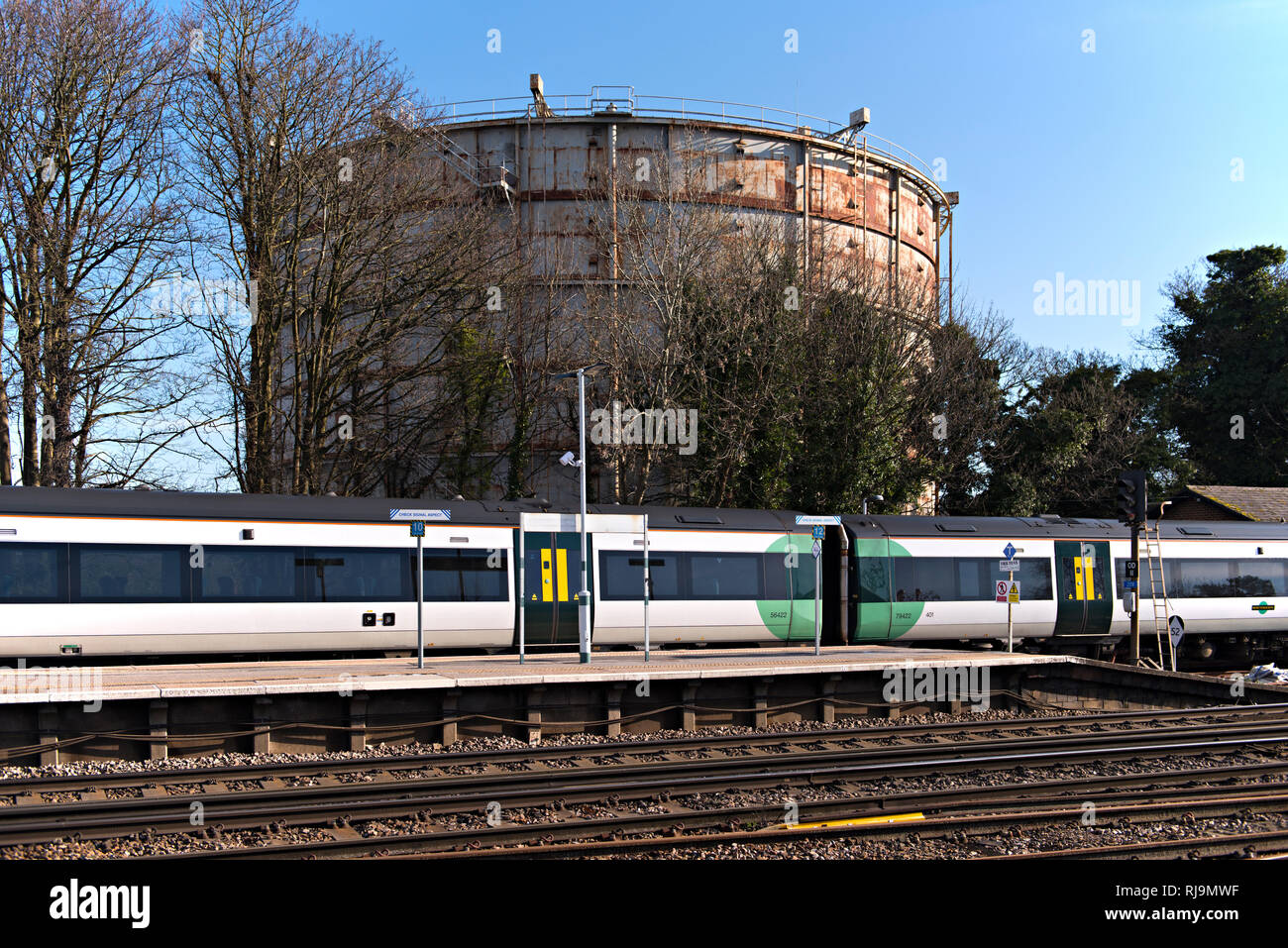 Oxted est une station de train Turbostar dans la plate-forme. Dans l'arrière-plan est le gazomètre Oxted devenue redondante et la démolition (2019) Banque D'Images