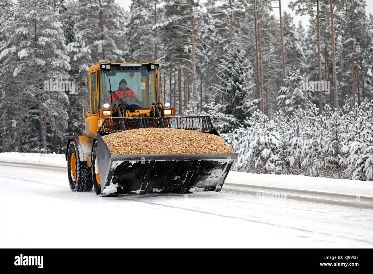 Salo, Finlande - le 25 janvier 2019 : opérateur de chargeur sur roues Volvo transporte une charge nette de l'eau dans l'océan de copeaux de neige le long de la pièce jointe lane en hiver. Banque D'Images