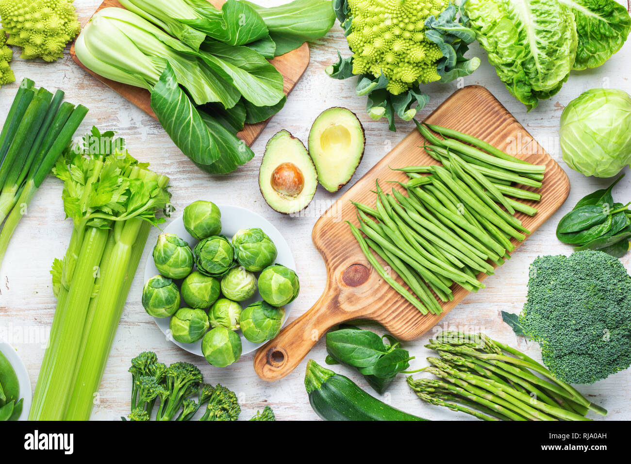 Concept vegan. Différents ingrédients, légumes verts sur tableau blanc les pousses de pois Haricots courgettes avocat céleri bok choy, vue du dessus Banque D'Images