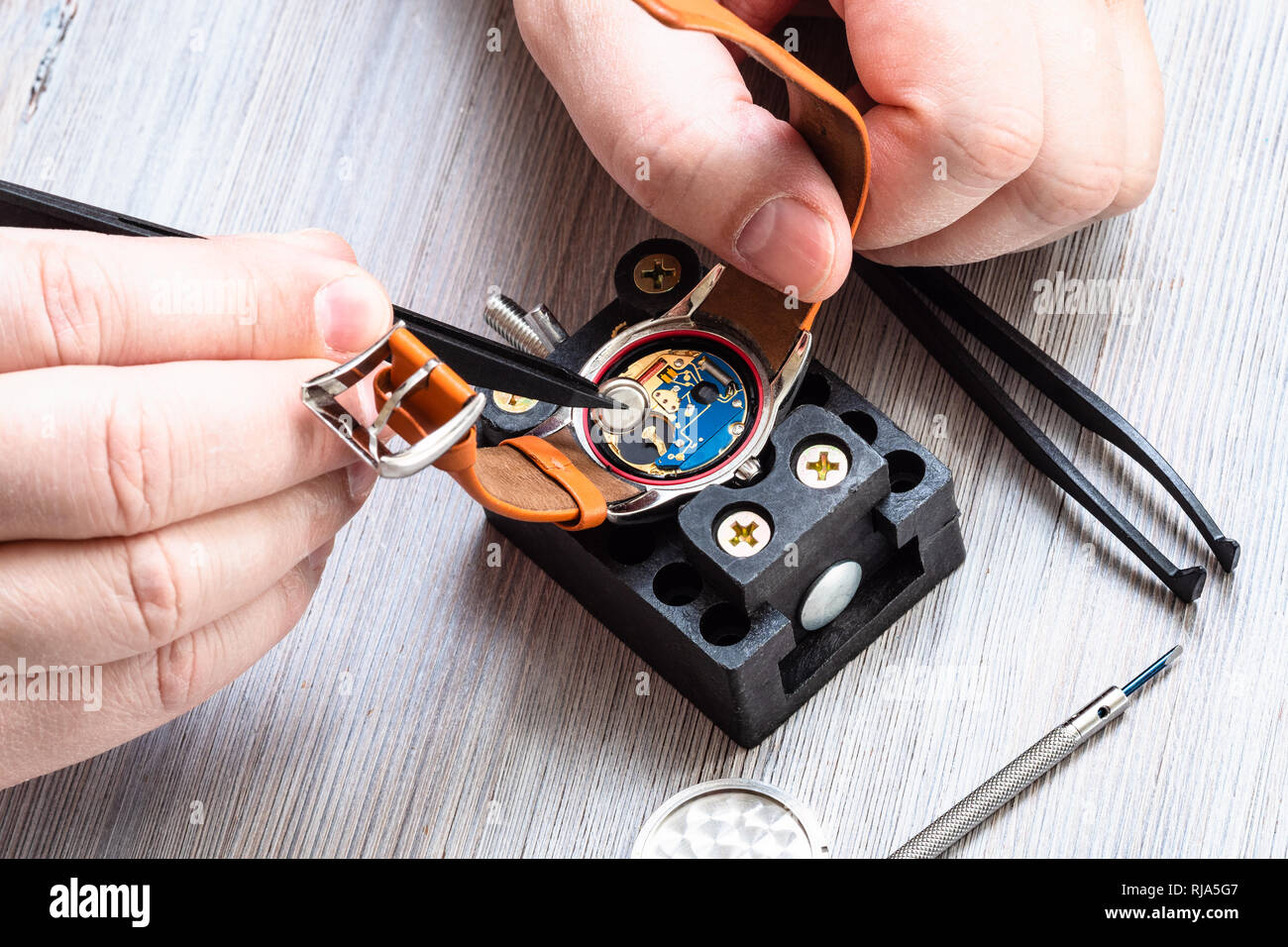 Atelier horloger réparateur montre - montre-bracelet quartz de batterie supprime avec des pinces en plastique sur la table en bois Banque D'Images