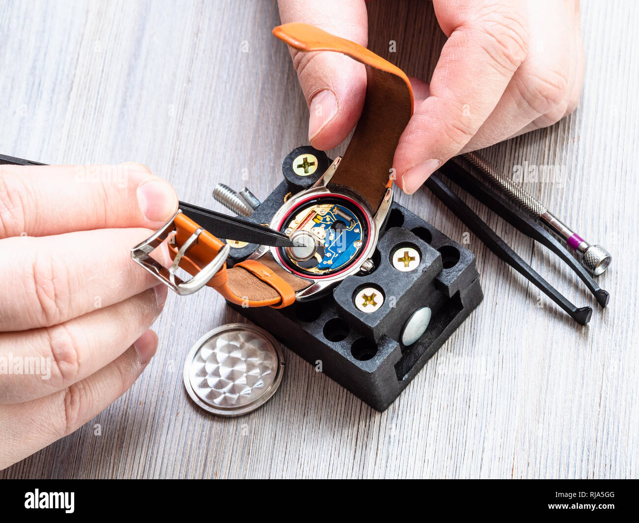 Atelier horloger réparateur montre - montre-bracelet quartz en batterie s'installe avec des pinces en plastique sur la table en bois Banque D'Images