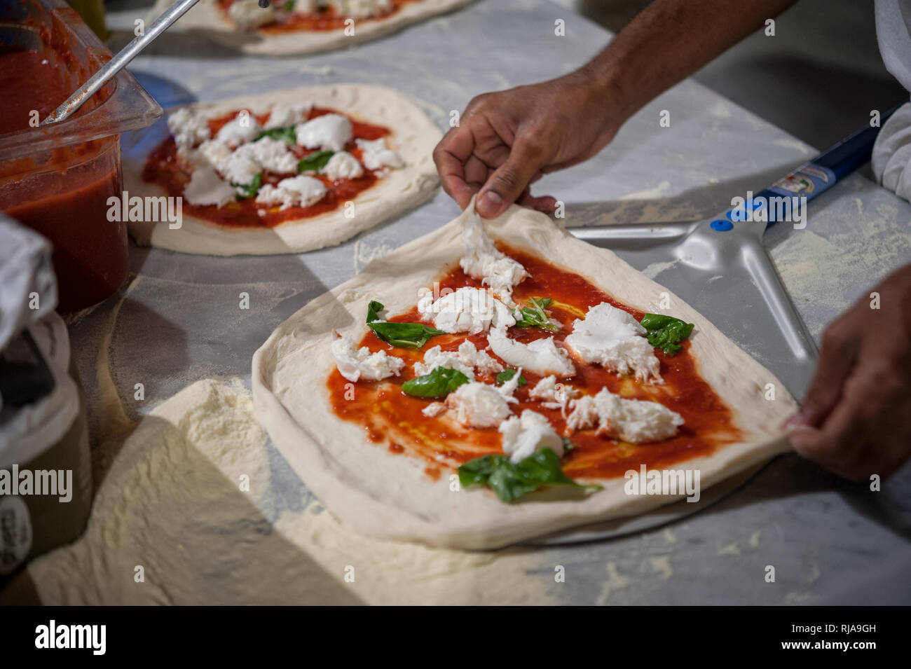 La préparation de Pizza Margherita sur un comptoir en marbre.Pizzaiolo met la pâte à pizza sur la pelure. Selective focus Banque D'Images