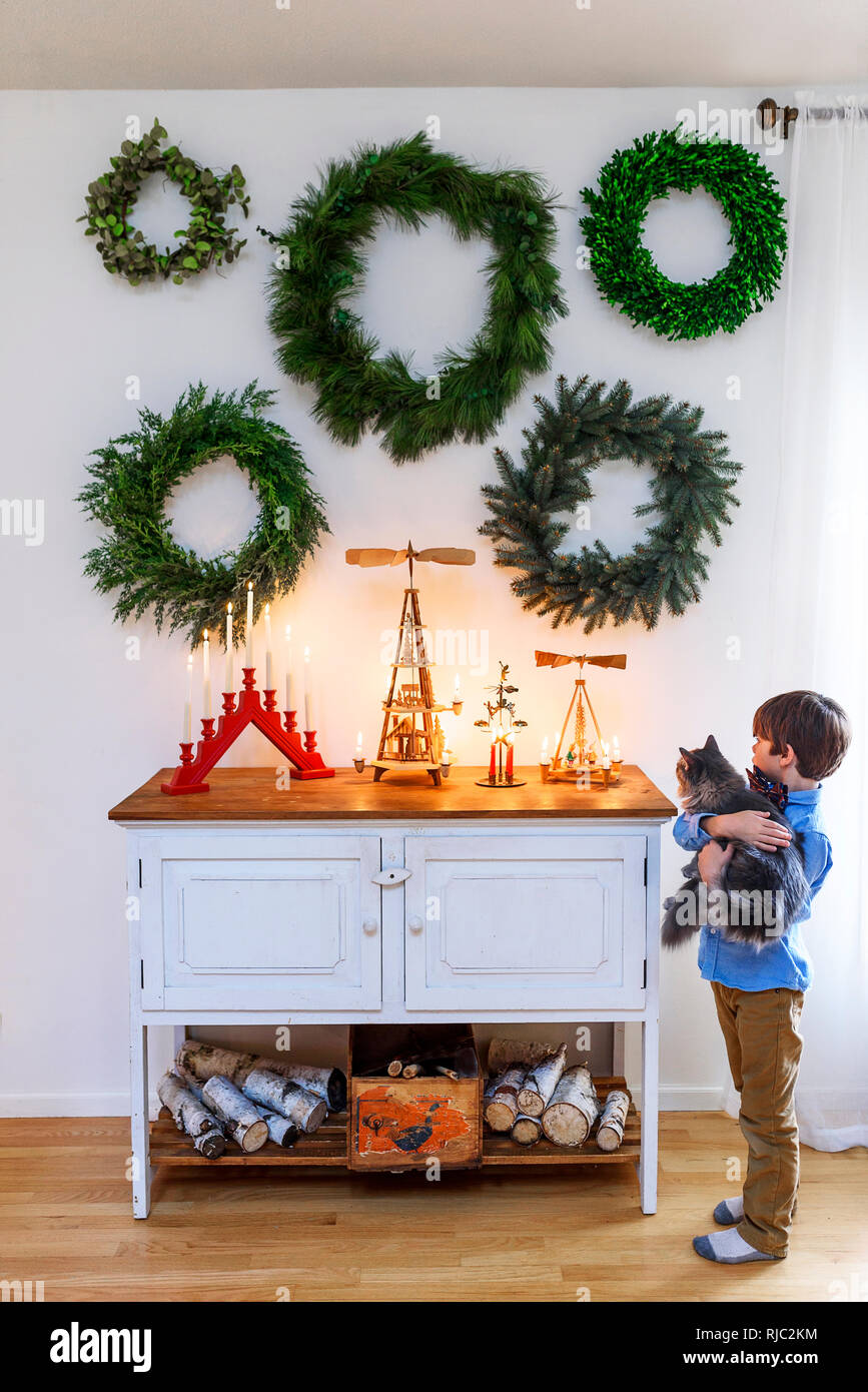 Garçon debout par un bahut avec son chat à la recherche de décorations de Noël Banque D'Images