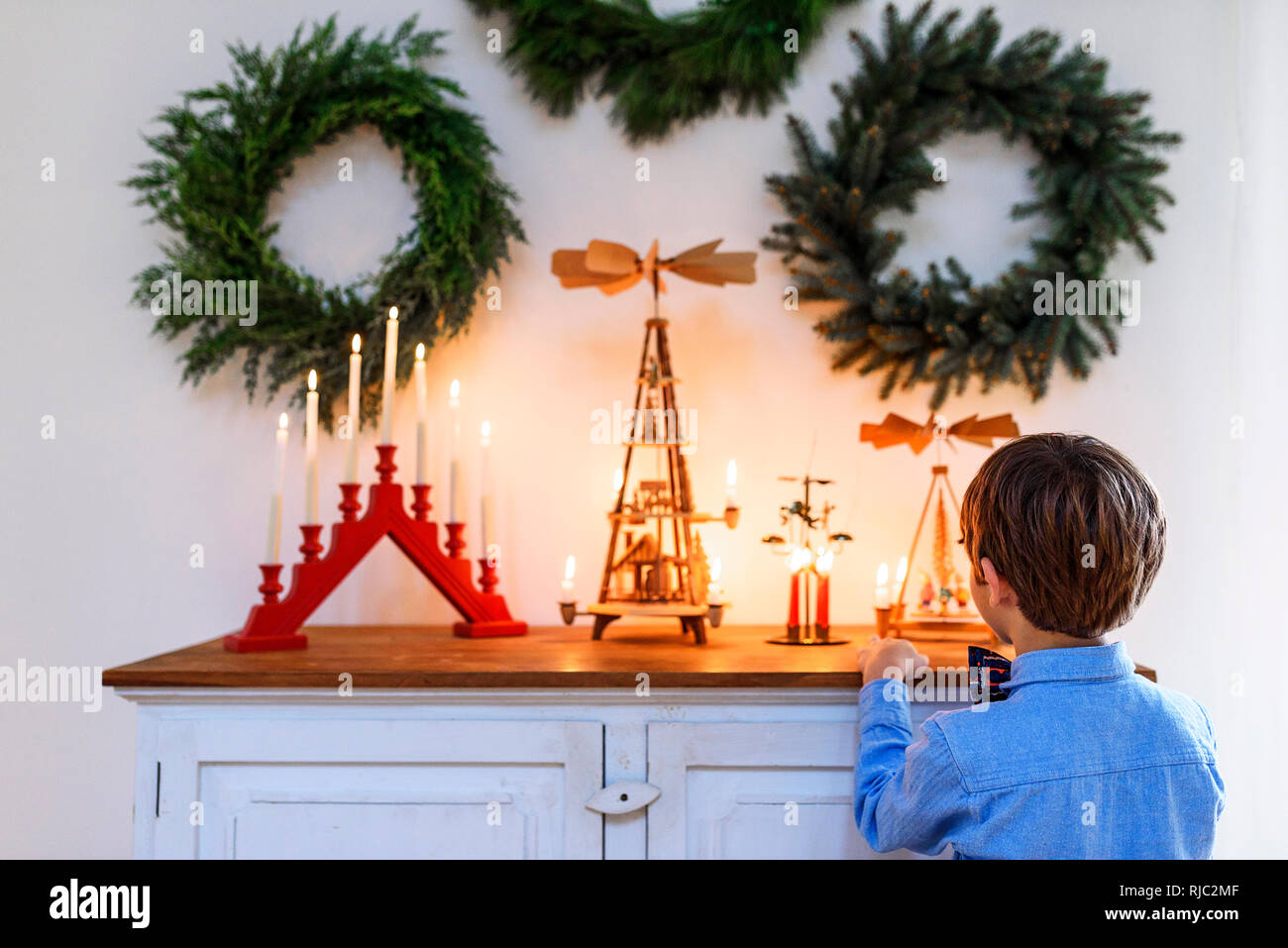 Garçon debout devant un buffet à la recherche de décorations de Noël Banque D'Images