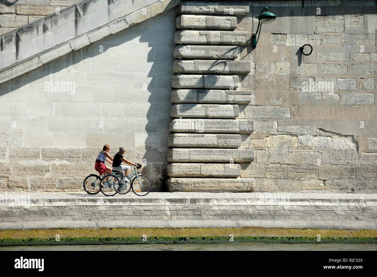 Deux cyclistes à vélo le long du quai de Seine, quai ou Quai de la Seine Paris France Banque D'Images