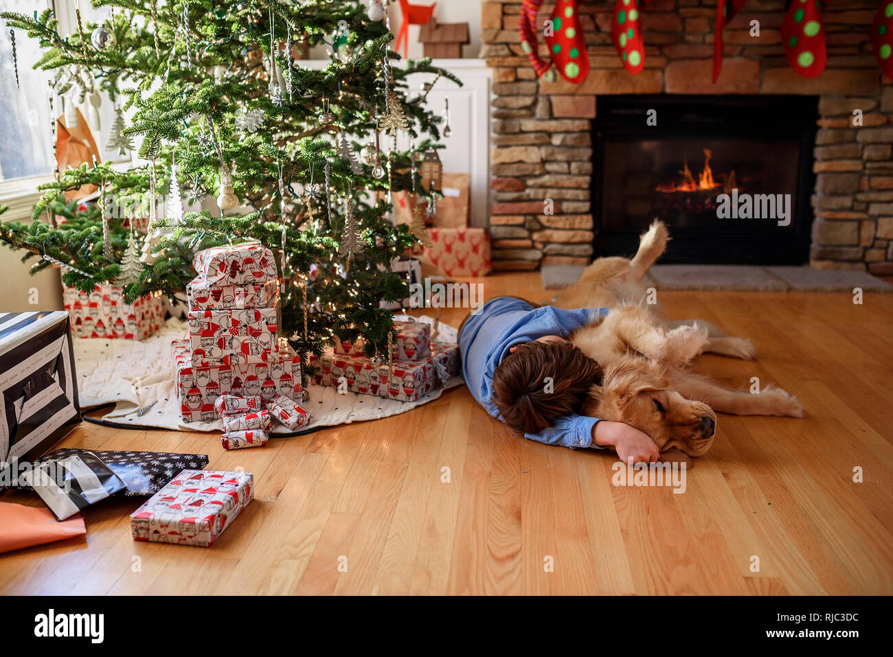 Garçon couché sur le sol en face d'un arbre de Noël de câliner son chien Banque D'Images