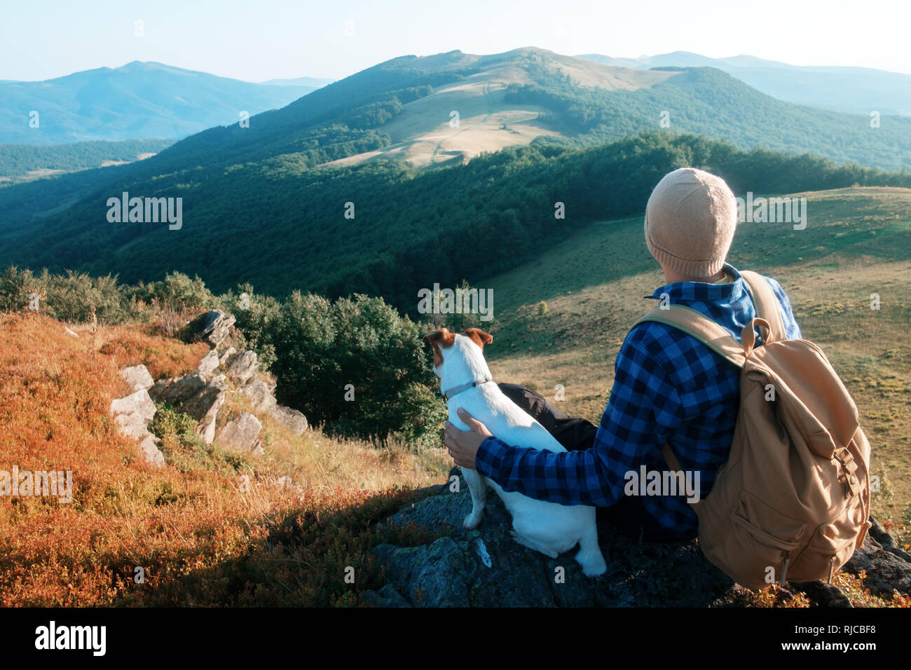 Tourisme à elle seule assise sur le bord de la falaise avec chien dans le contexte d'un incroyable paysage de montagne. Journée ensoleillée et ciel bleu Banque D'Images