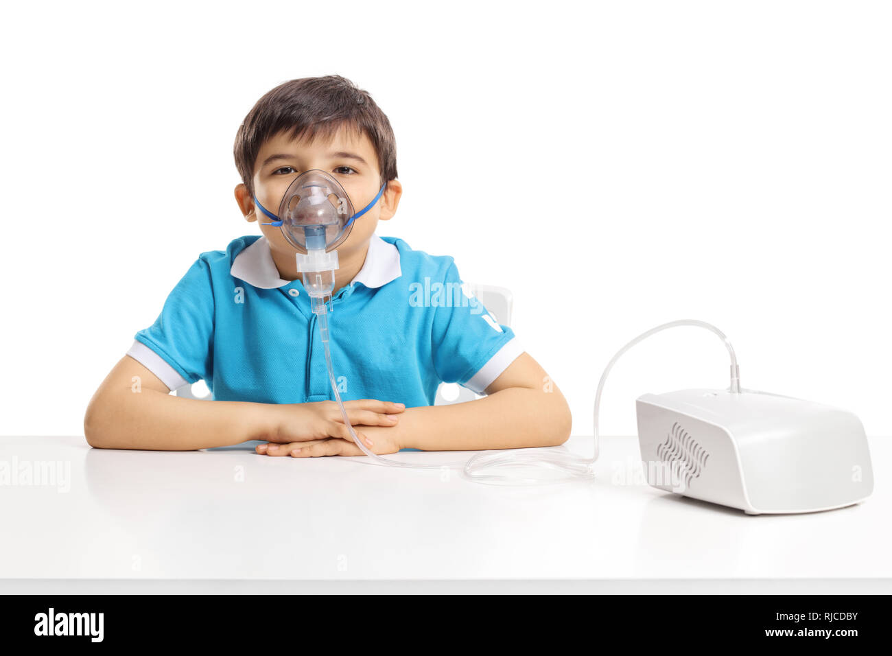 Garçon assis à une table avec masque inhalation isolé sur fond blanc Banque D'Images