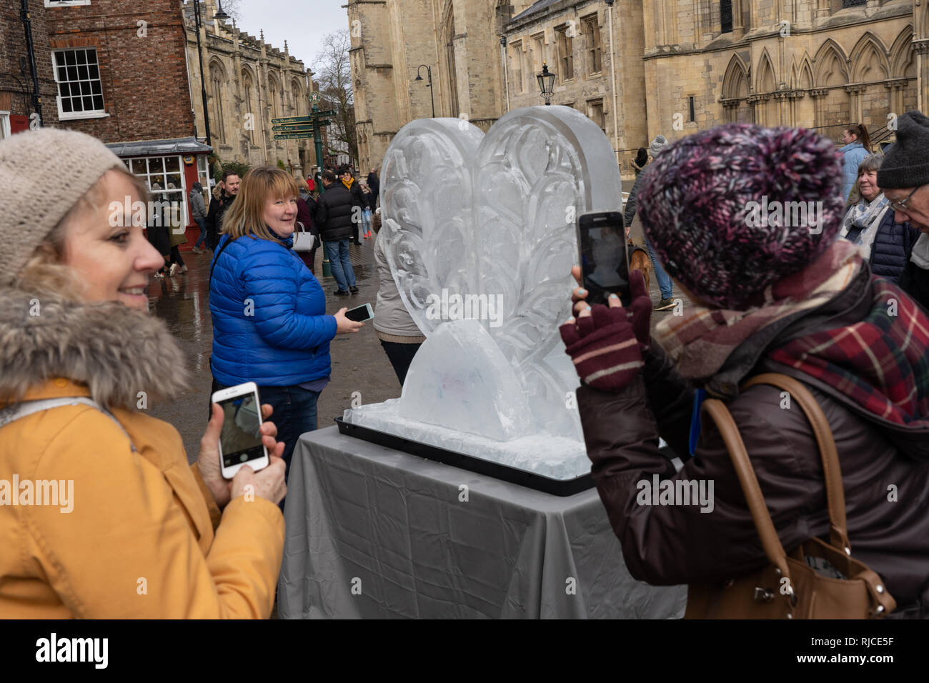 Le cœur de la sculpture sur glace du Yorkshire est photographié par deux femmes avec leur téléphone portable le long de la piste de glace de York, dans le North Yorkshire, au Royaume-Uni Banque D'Images