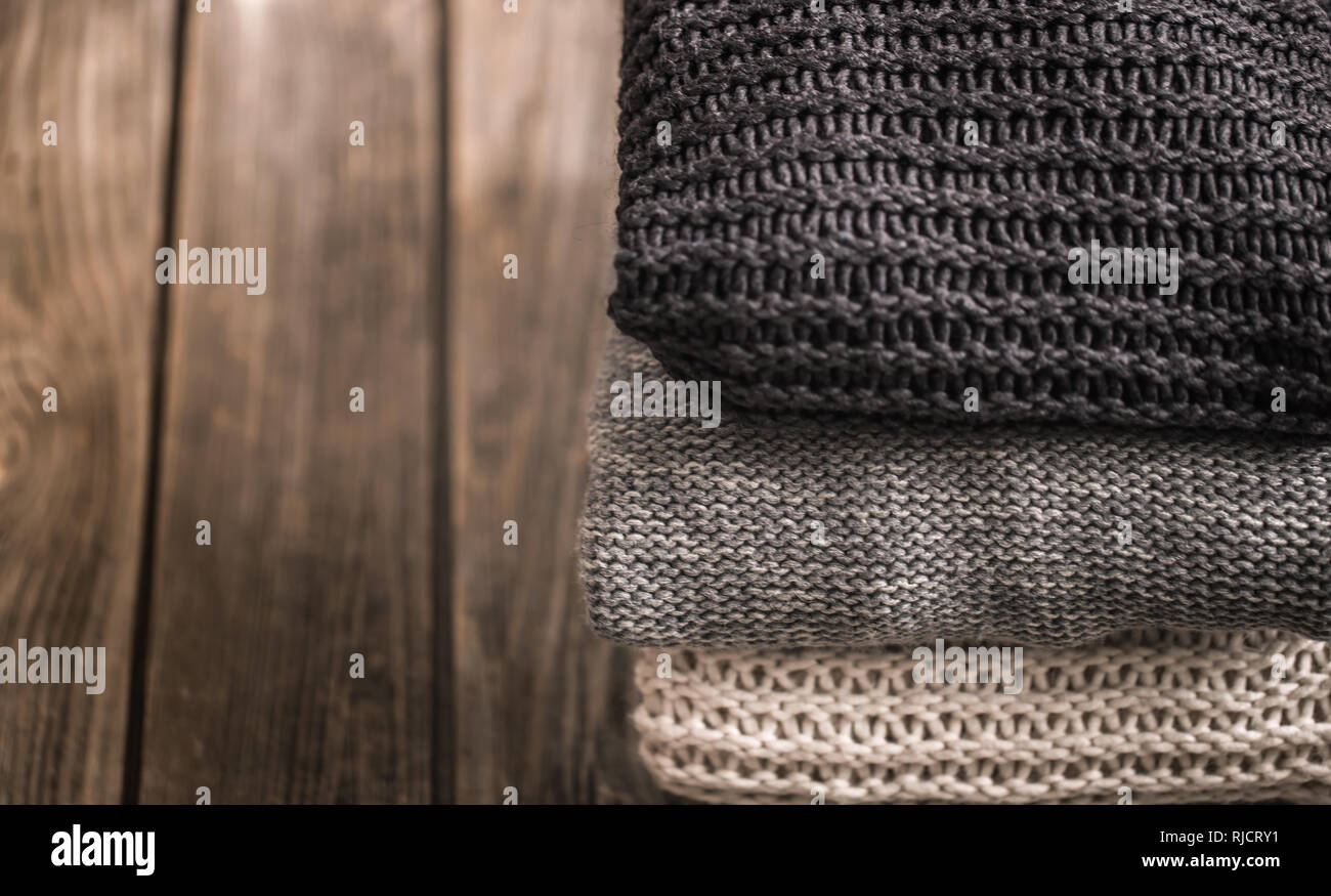 Une pile de pulls en blanc, gris et noir sur un fond de bois, close-up, de l'espace pour le texte Banque D'Images