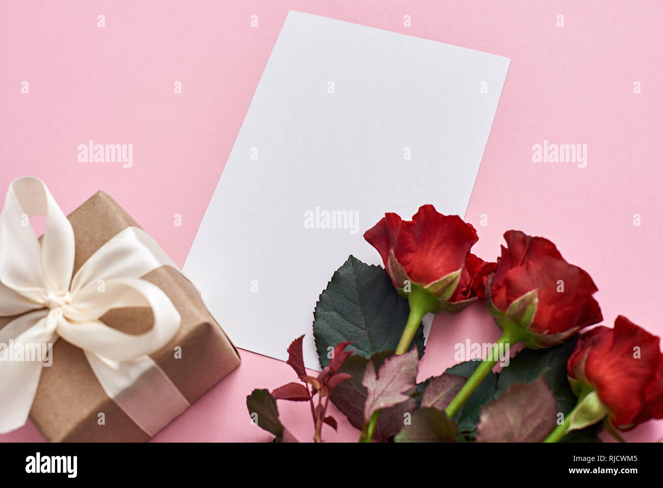 Être romantique...Vue de dessus de cadeau pour elle : des roses rouges, boîte cadeau et papier Remarque Pour lettre d'amour. Fond rose. Banque D'Images Être romantique...Vue de dessus de cadeau pour elle : des roses rouges, boîte cadeau et papier Remarque Pour lettre d'amour. Fond rose. Banque D'Images