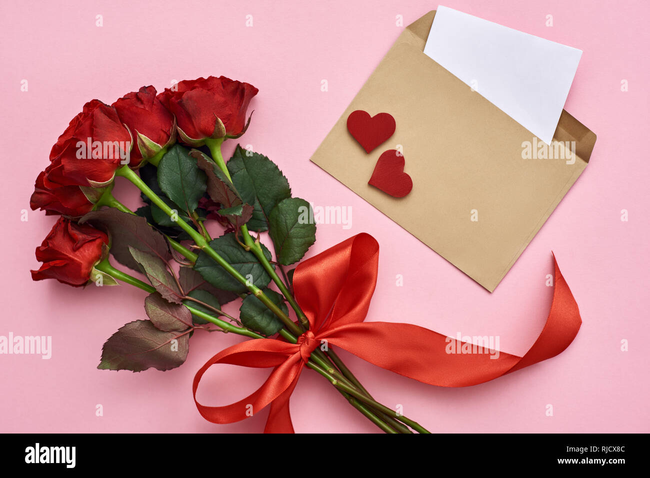 L'amour vrai. Avec enveloppe papier remarque, bouquet de roses avec ruban rouge sur fond rose Banque D'Images L'amour vrai. Avec enveloppe papier remarque, bouquet de roses avec ruban rouge sur fond rose Banque D'Images