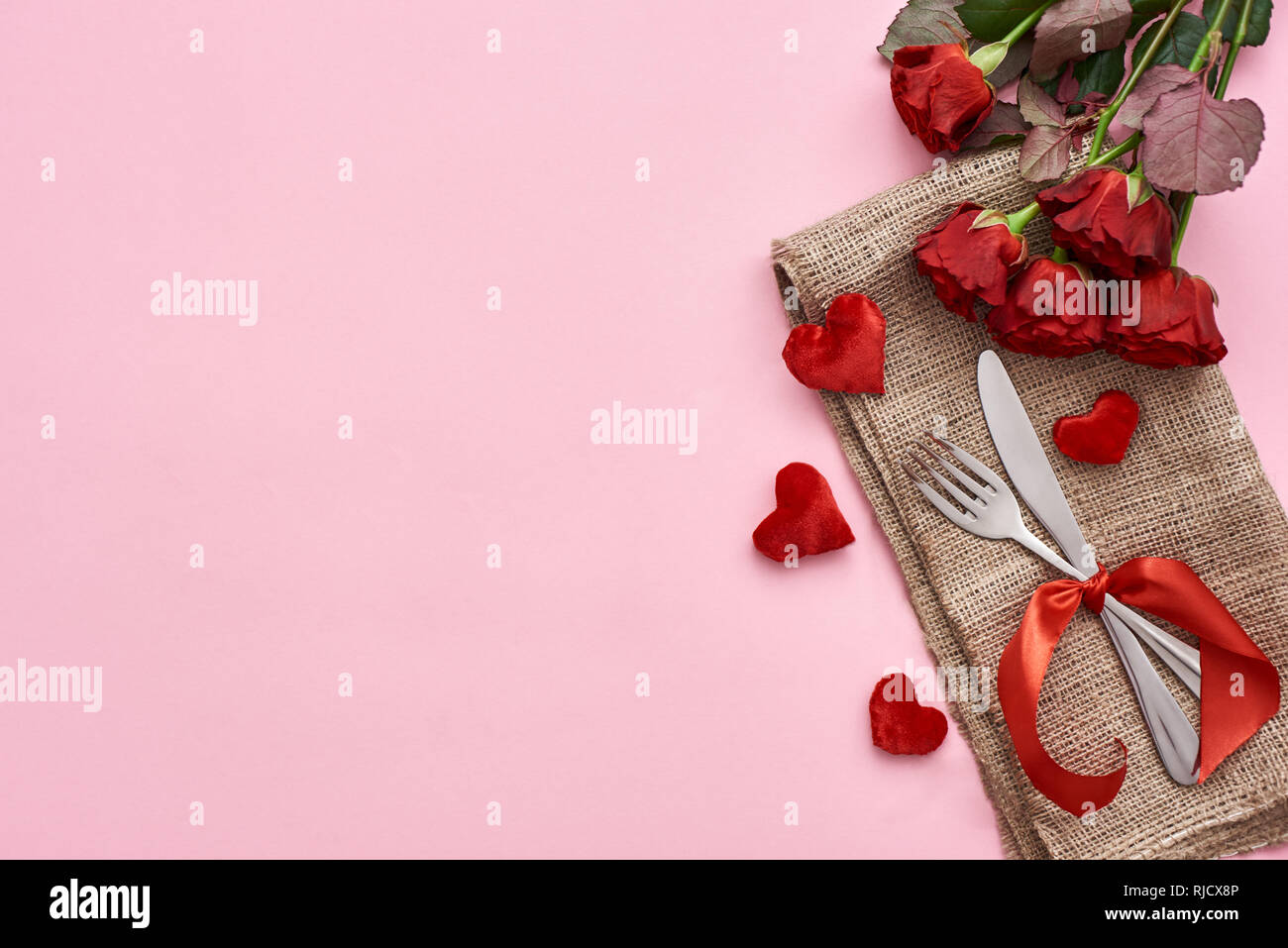 Dîner romantique. Close up de table avec des roses rouges et des cœurs. Fond rose Banque D'Images