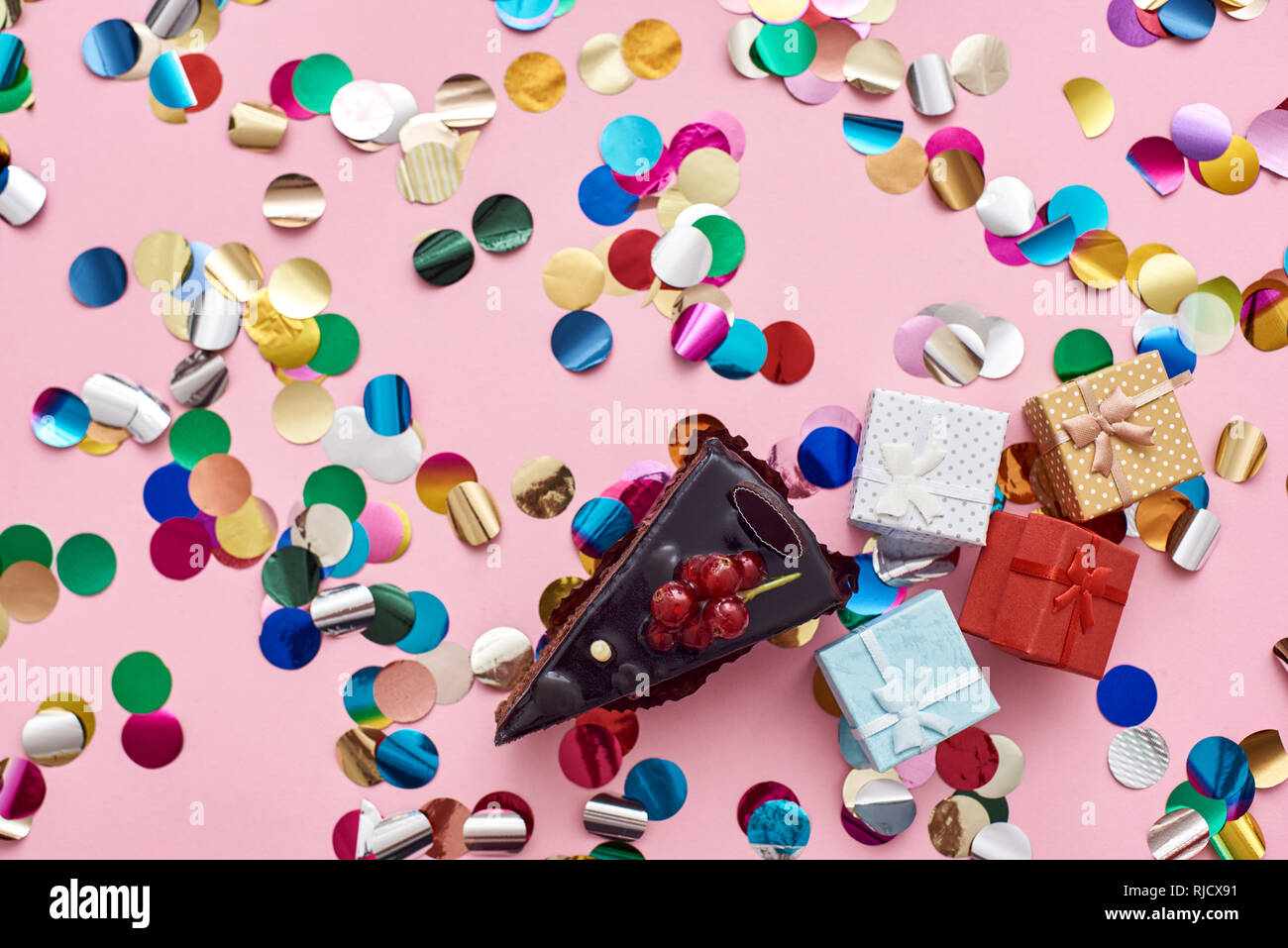 Peu n'a jamais tué personne. Un morceau de gâteau au chocolat avec des boîtes cadeau mignon et coloré de confettis. Fond rose Banque D'Images