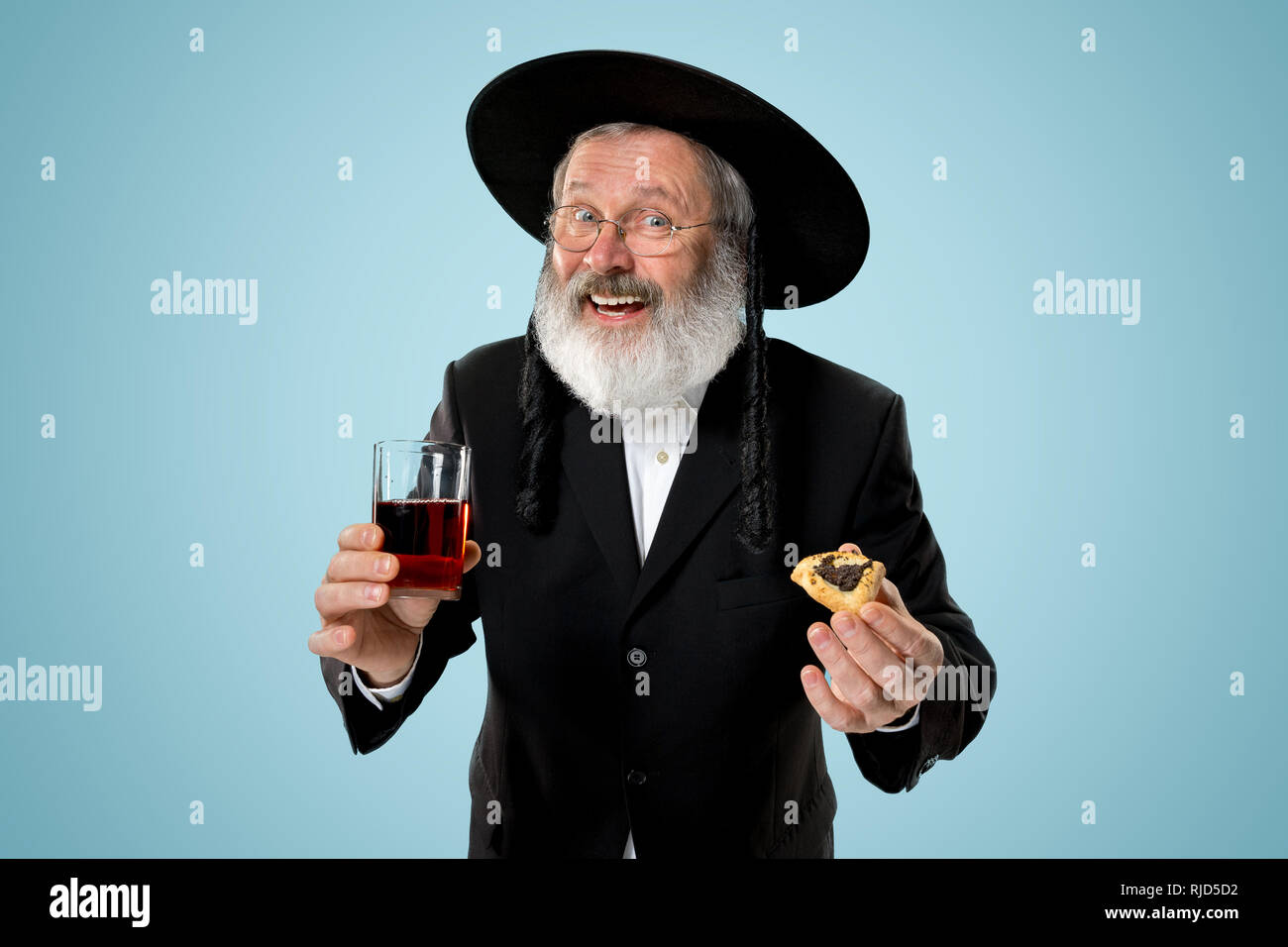 L'homme Juif orthodoxe avec chapeau noir avec Hamantaschen cookies pour fête juive de Pourim au studio. La purim, juifs, festival, fête, célébration, le judaïsme, pâtisserie, tradition, cookie, la religion concept Banque D'Images