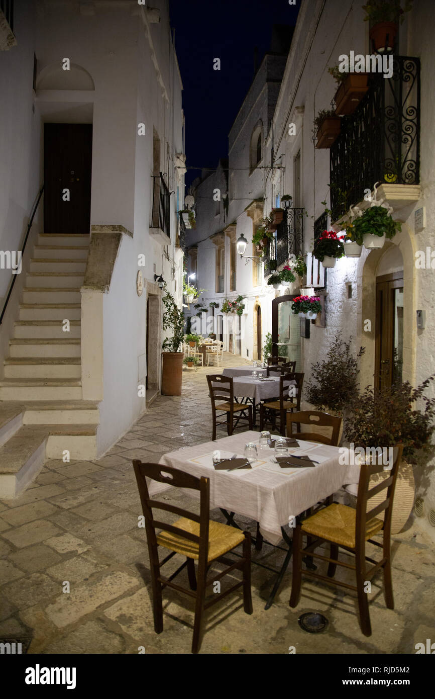 Rue blanche étroite et restaurant à Locorotondo la nuit, province de Bari, Italie Banque D'Images