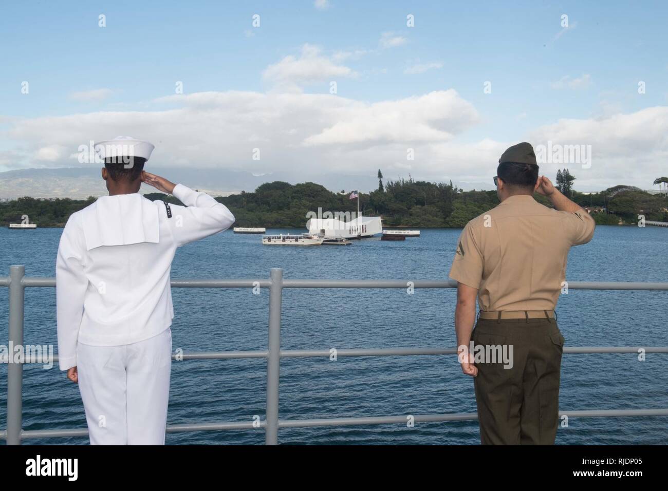 PEARL HARBOR (janv. 24, 2018) Un marin et un milieu marin à bord du navire de débarquement quai amphibie USS Pearl Harbor (LSD 52) rendre les hommages le navire passe le USS Arizona Memorial tandis qu'au départ de New York après une visite du port. Pearl Harbor est une partie de l'Amérique du groupe amphibie, à 15e Marine Expeditionary Unit (MEU) 15e, est de retour d'un déploiement de 7 mois aux États-Unis 3e, 5e et 7e flotte zone d'opérations. Banque D'Images
