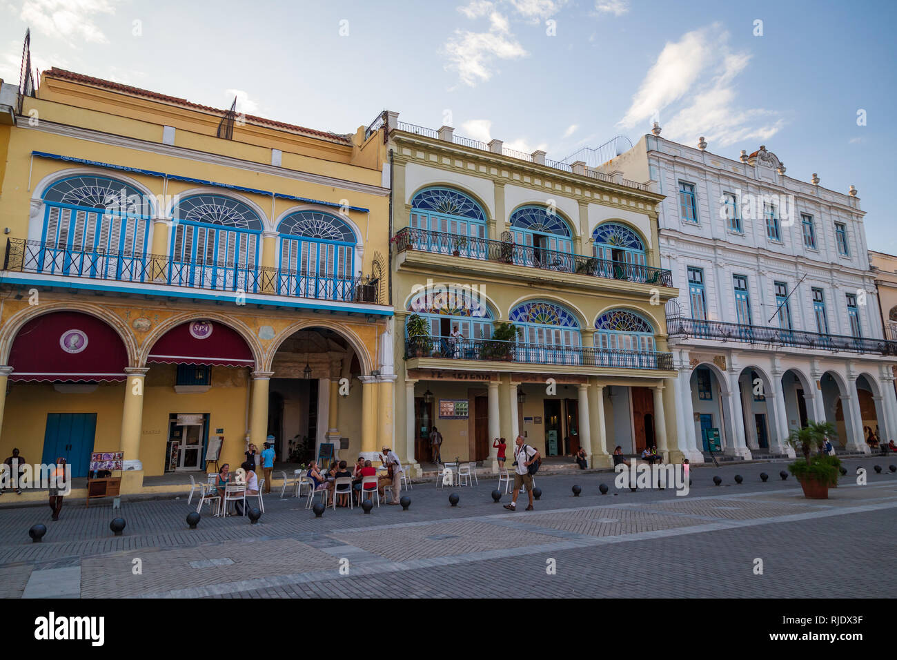 Un mur à l'autre des bâtiments de style colonial espagnol avec des gens assis à l'extérieur d'un café sur la place de la vieille ville de Plaza Vieja à La Havane Cuba Banque D'Images
