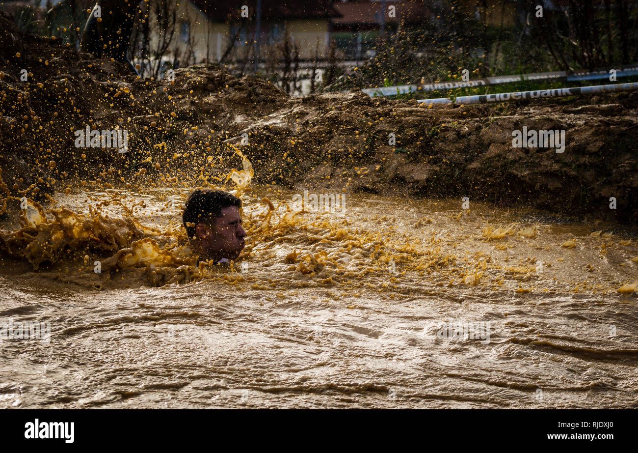 Gijon, Asturias, Espagne - Février 04, 2019 : Un coureur splash après avoir sauté dans la fosse à la boue racer. Banque D'Images