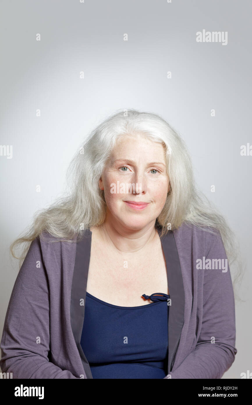 Portrait d'une jolie femme mature avec de beaux longs cheveux gris in front of white background, copiez l'espace. Banque D'Images