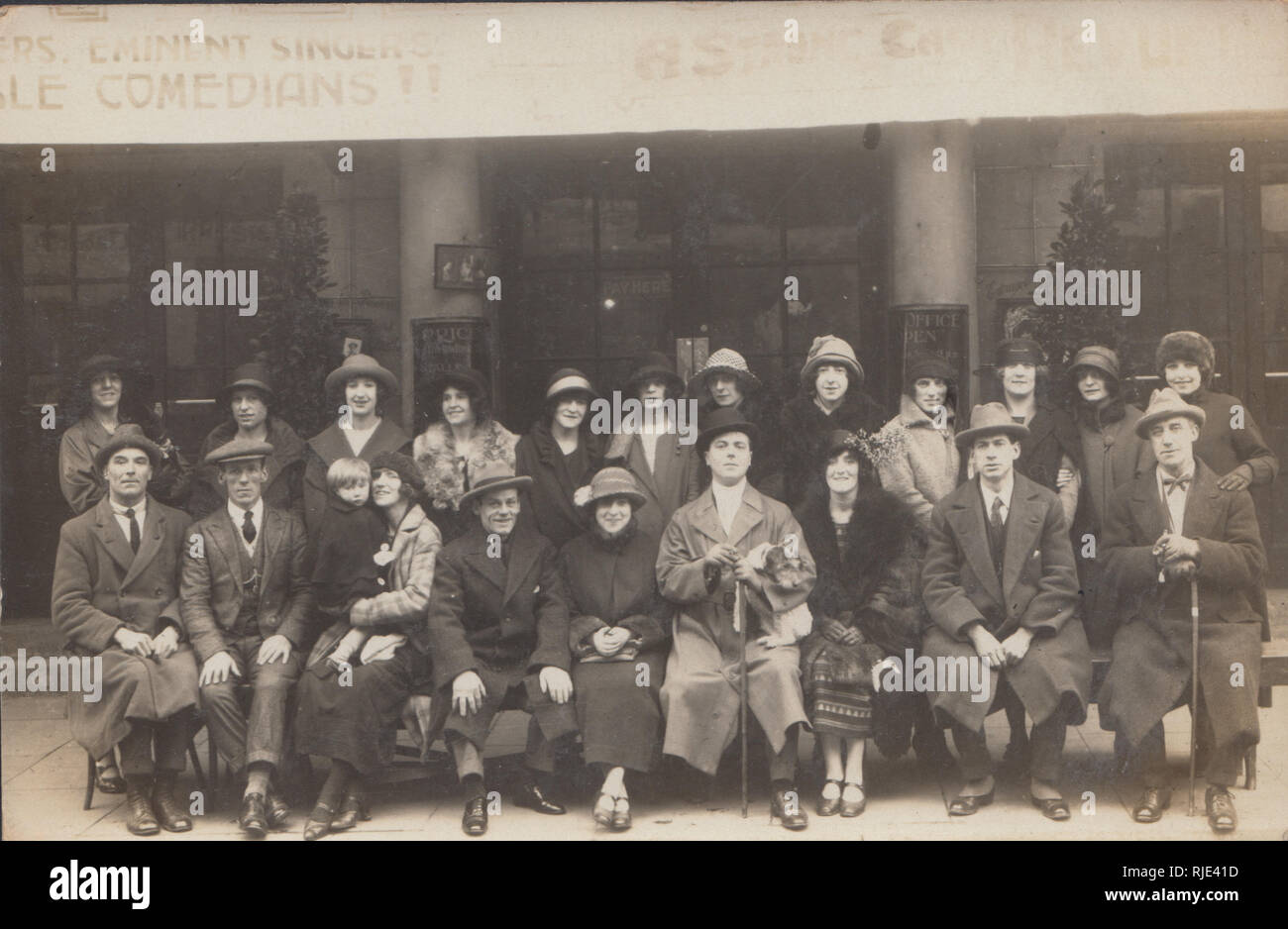 Vintage Carte postale photographique montrant un groupe de comédiens assis à l'avant d'un théâtre. Banque D'Images