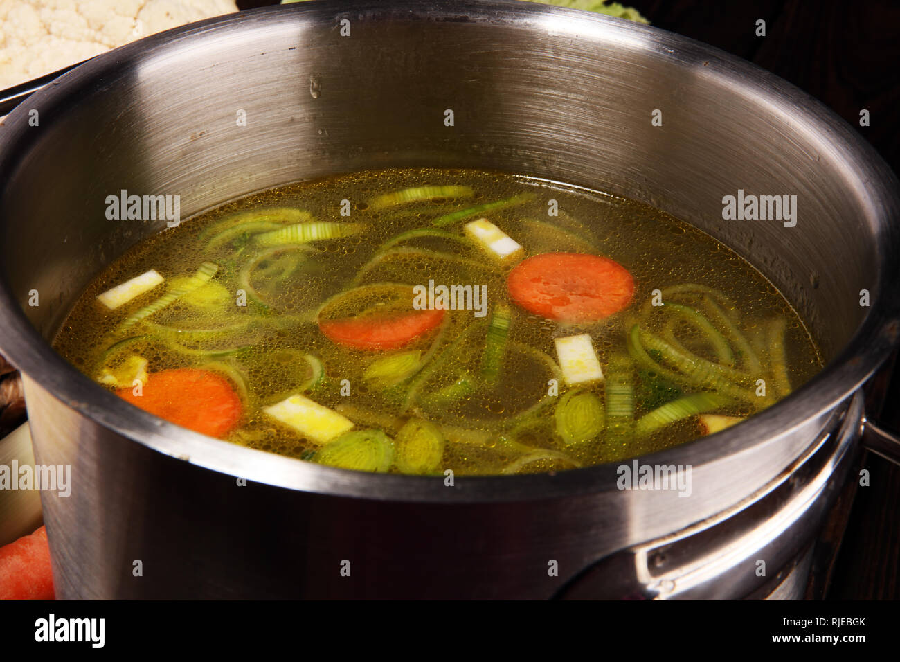 Bouillon avec carottes, oignons divers légumes frais dans un pot - frais colorés clear spring soupe. Cuisine végétarienne paysage rural bouillon Banque D'Images