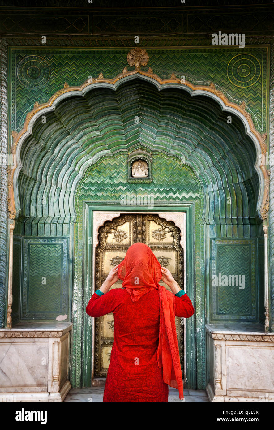 Femme indienne en écharpe rouge à la porte à porte verte dans la région de palais de la ville de Jaipur, Rajasthan, Inde. L'espace pour votre texte, peut être utilisé comme livre ou magazine Banque D'Images