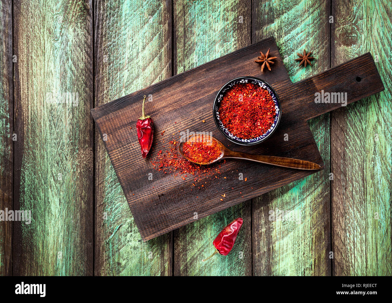Paprika en poudre et piment rouge foncé sur une planche à découper à table en bois vert Banque D'Images