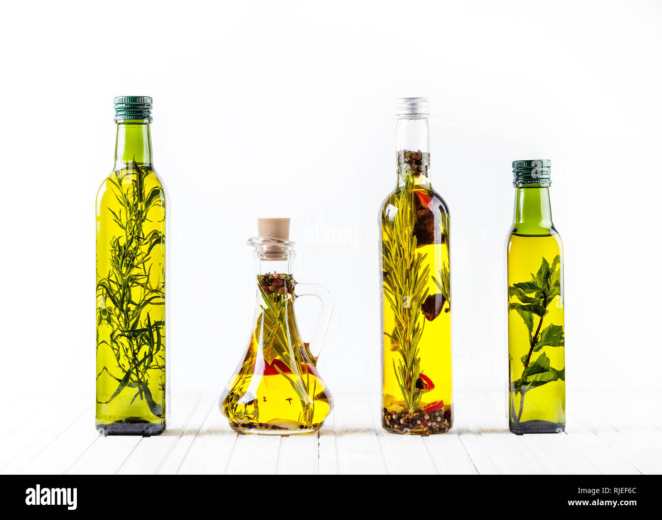 Bouteille d'huile faite maison avec des herbes et épices sur fond blanc. Espace libre pour le texte. Banque D'Images
