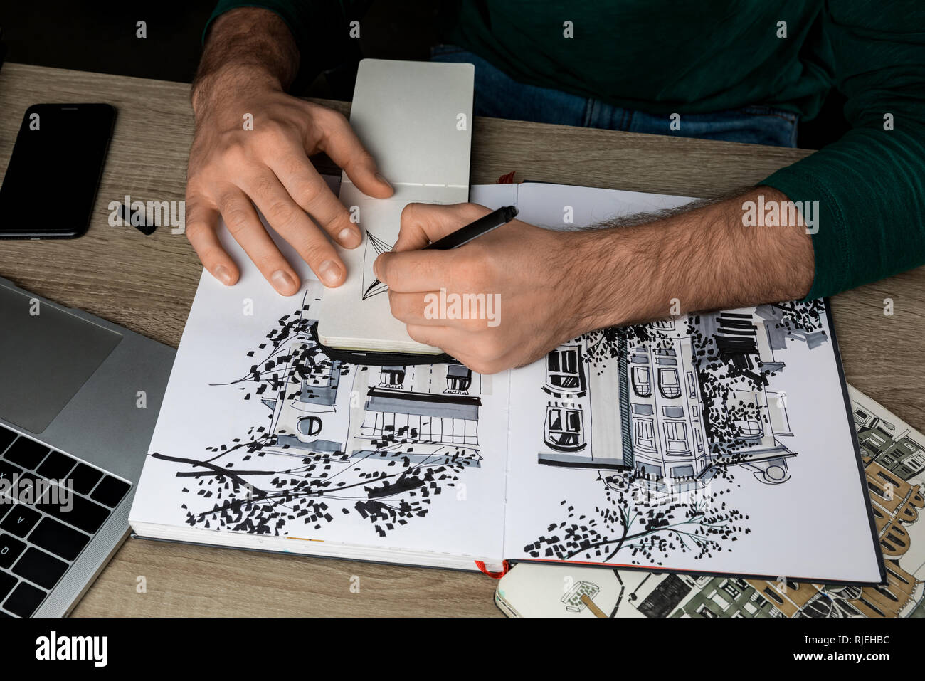 Vue de dessus du mans mains dimensions dans l'ordinateur portable sur une table en bois à côté d'albums et gadgets Banque D'Images