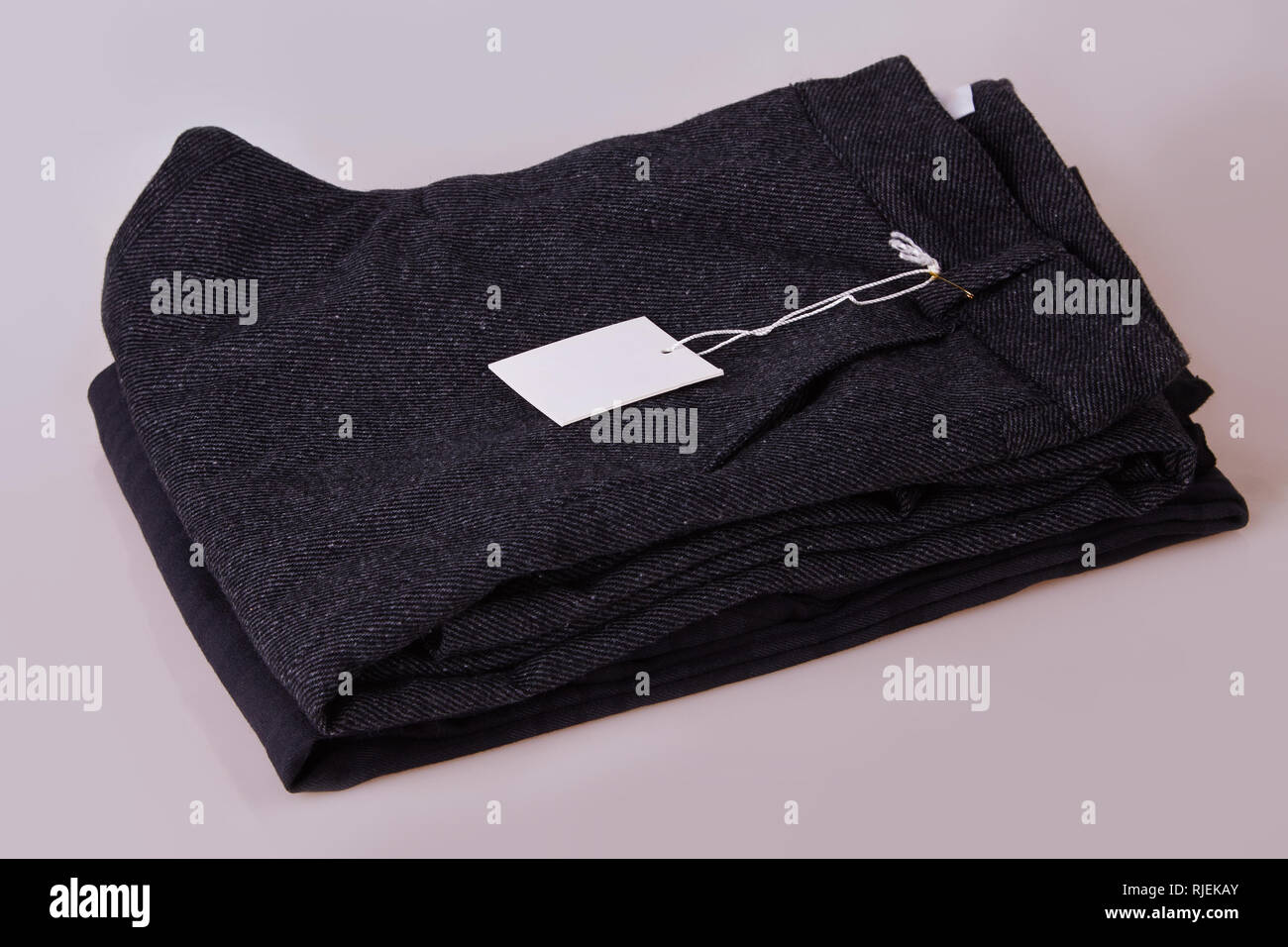 Pantalon gris foncé organique. Pantalon pile sur un fond blanc. Tag vêtements. Blank white label tag prix Banque D'Images
