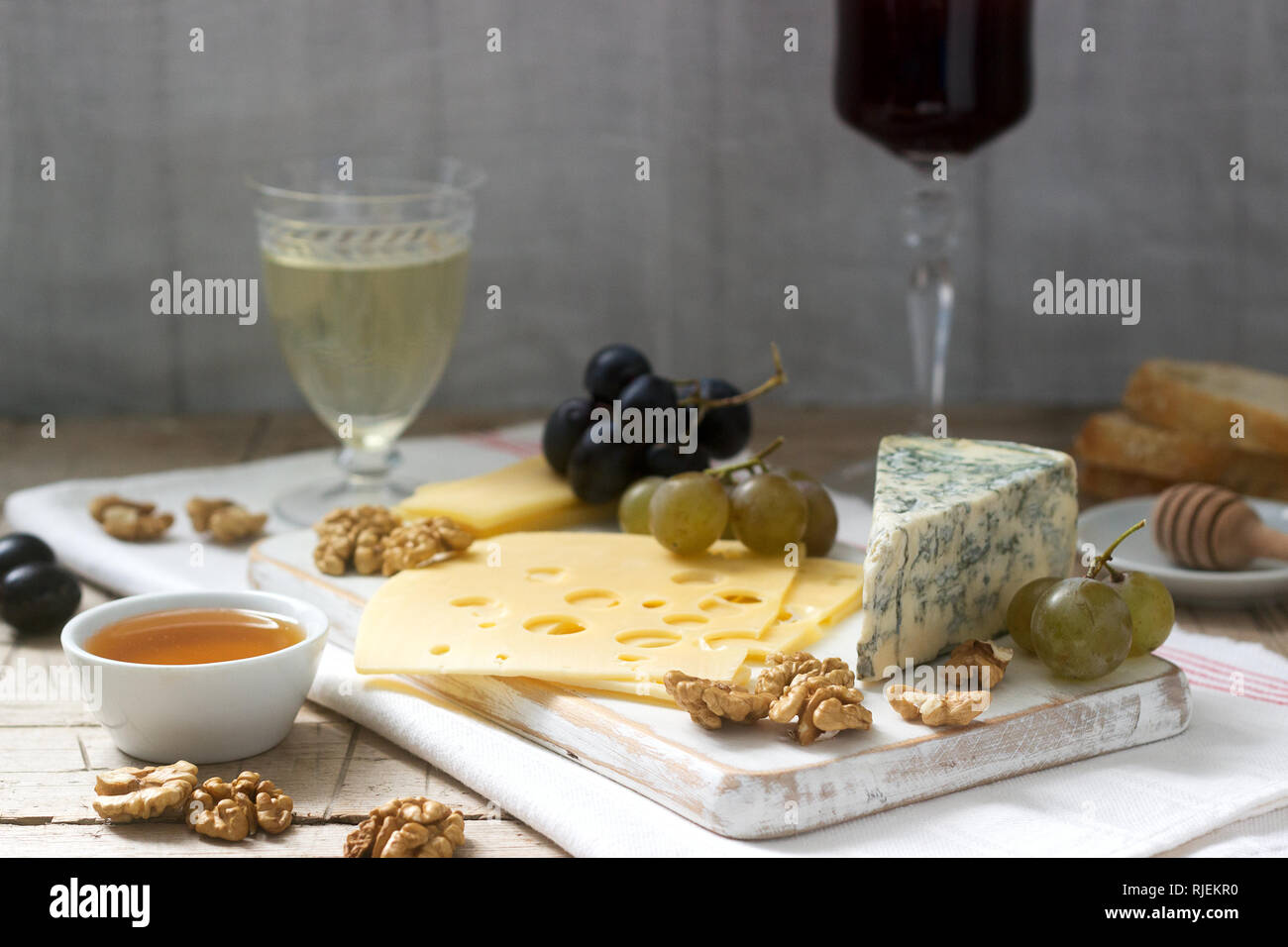 Apéritifs de différents types de fromage, raisins, noix et miel, servi avec des vins blanc et rouge. Style rustique. Banque D'Images