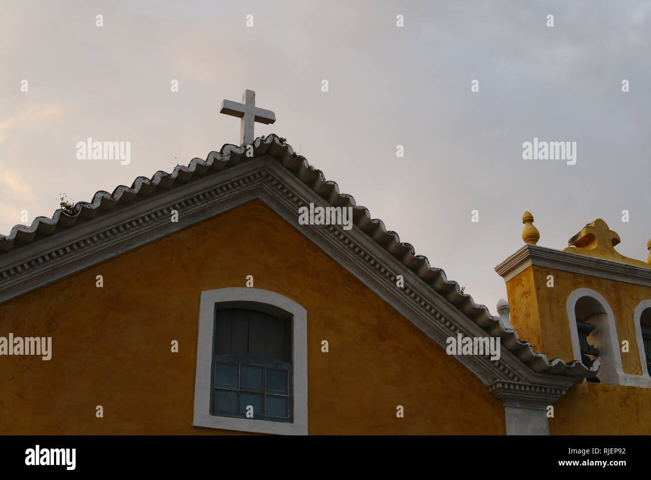 Haut d'une église catholique traditionnel en Amérique latine. Un bâtiment jaune avec une croix blanche. Banque D'Images