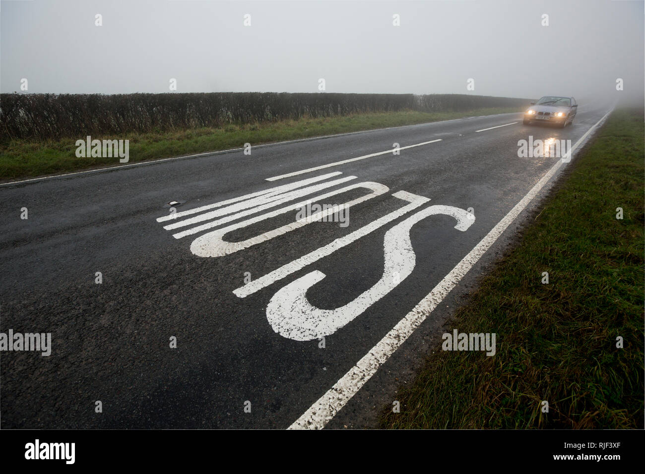 Une voiture avec ses phares sur l'approche d'un signe sur une faible bruine, brouillard journée dans Nord du Dorset England UK GO Banque D'Images