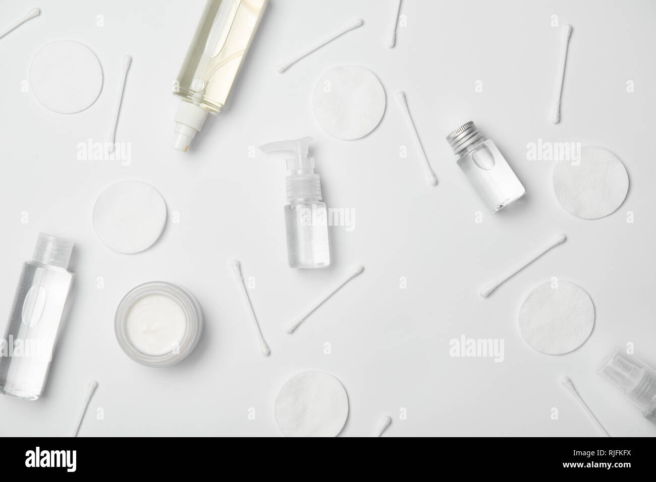 Vue de dessus de différents flacons cosmétiques, bâtonnets de coton à démaquiller et sur fond blanc Banque D'Images