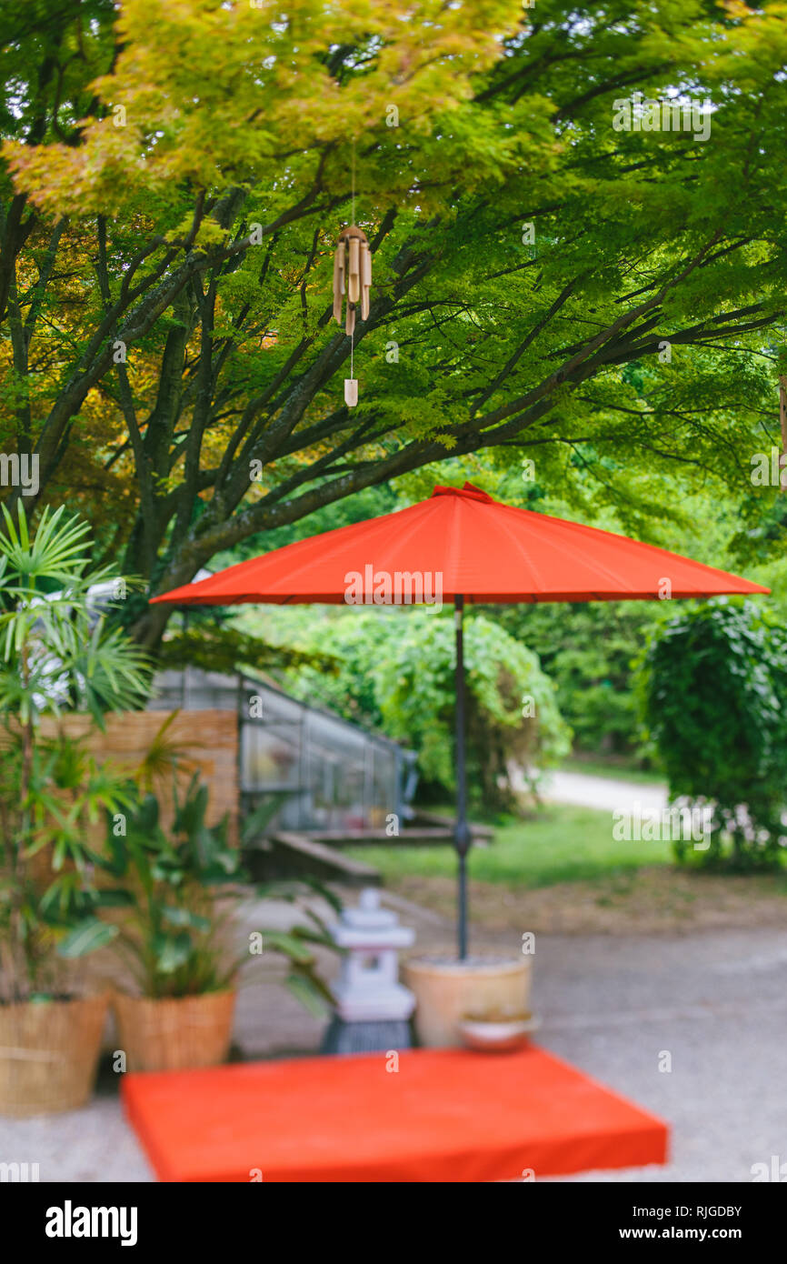 Carillon éolien japonais en bambou en bois cloches transmis arbre dans le jardin japonais avec parapluie rouge et poteries - Tilt-shift effet lentille Banque D'Images