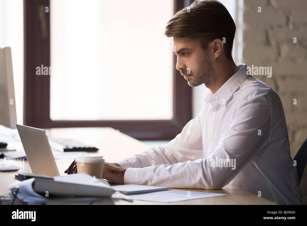 L'accent employé occupé à travailler à laptop in office Banque D'Images