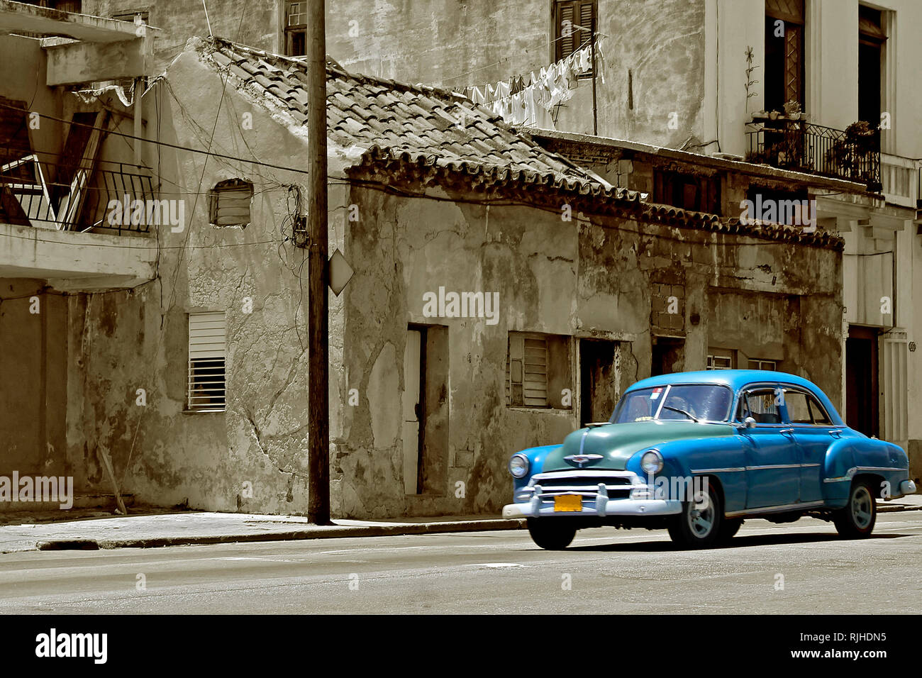 Voiture vintage bleu sur Havana street avec de vieilles maisons délabrées, sépia de l'image de style Banque D'Images