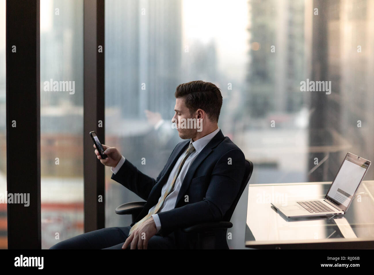 Businessman using smartphone dans gratte-ciel Banque D'Images