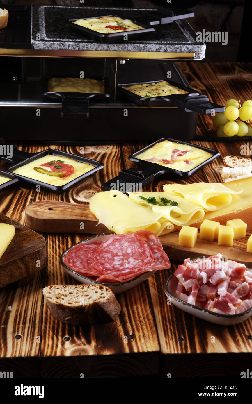 Délicieux fromage à raclette fondue suisse traditionnel servi dans des poêlons au salami Banque D'Images Délicieux fromage à raclette fondue suisse traditionnel servi dans des poêlons au salami Banque D'Images