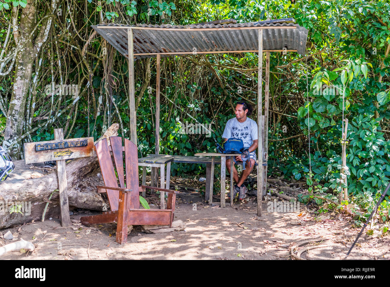 Une photo d'un homme assis dans le modeste bureau de tourisme à l'entrée de la magnifique et unique parc national de Corcovado au Costa Rica Banque D'Images