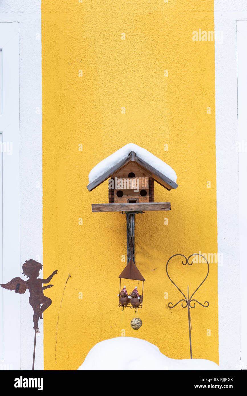 Home-made de l'oiseau en bois convoyeur en hiver, sous la neige. Mur jaune Banque D'Images