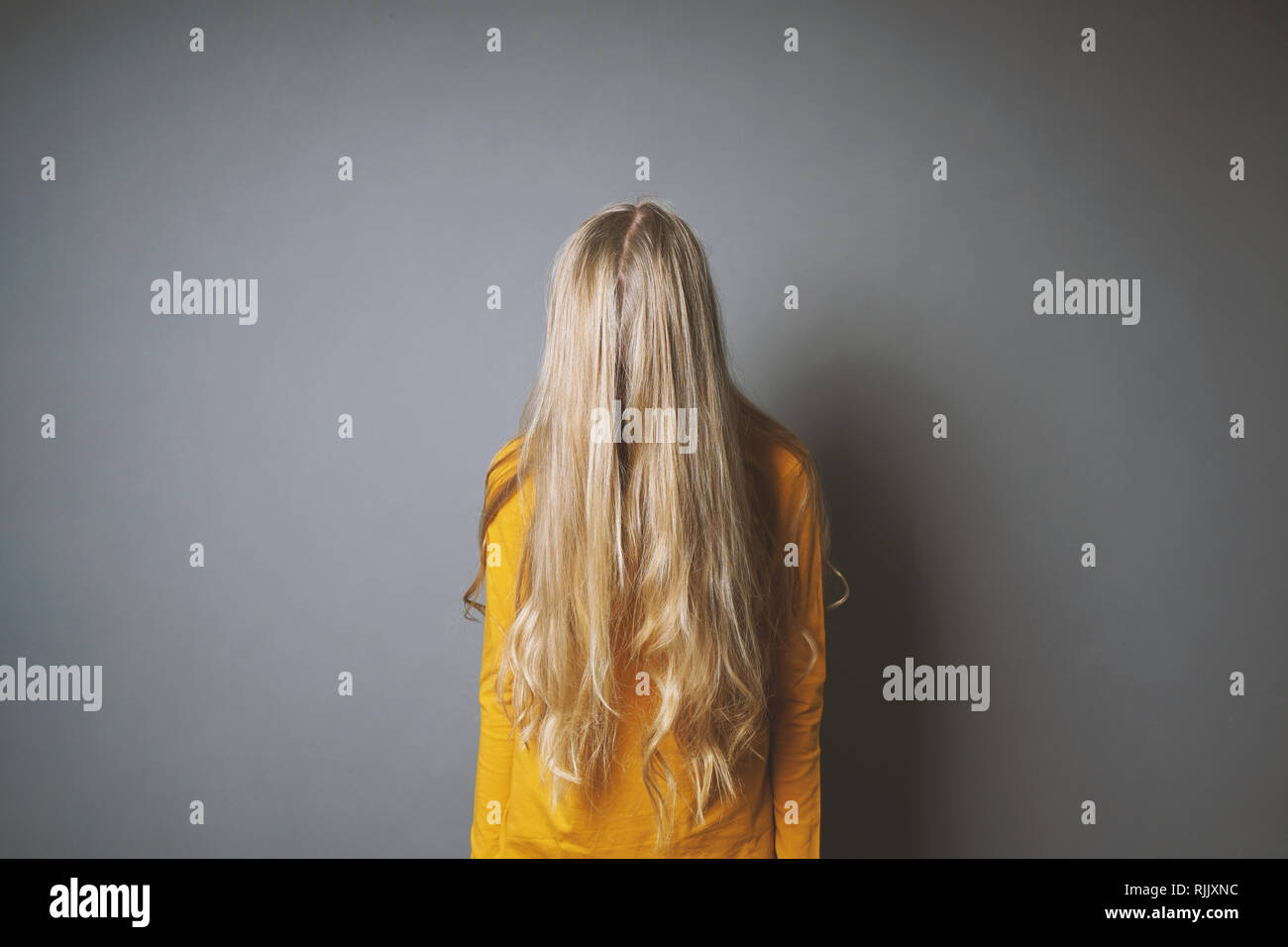 Jeune femme déprimée cachant son visage derrière de longs cheveux blonds Banque D'Images