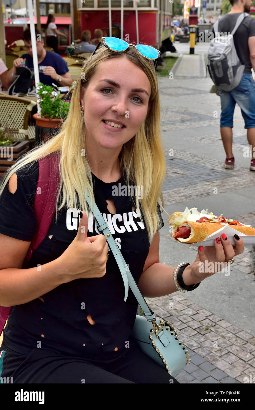 Belle femme aux cheveux blond avec des lunettes eating hot-dog Banque D'Images